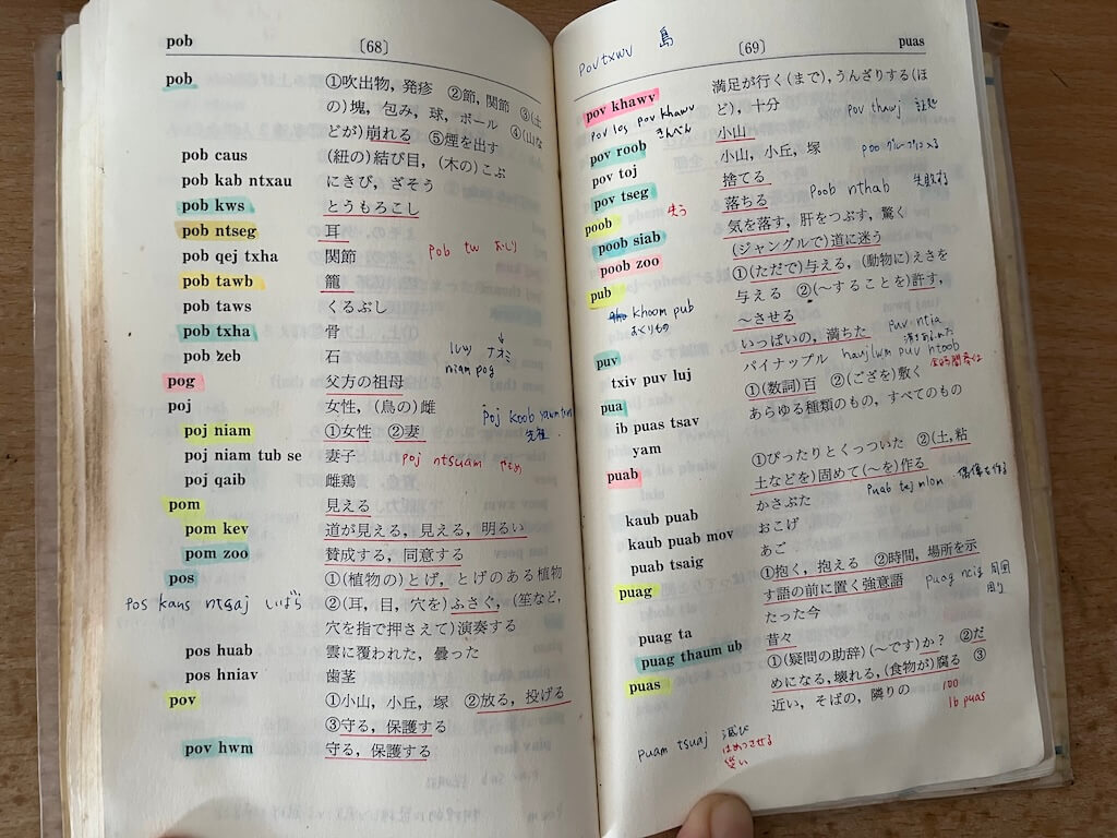 小口が黒くなるまで使い込まれたモン語の単語帳。マーカーや手書きのメモがびっしりと書き込まれており、未知の言語を習得するための徹底的な学習姿勢を示しています。