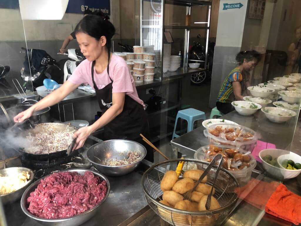 ベトナムのローカル食堂で調理をする年上の女性の様子。年上の女性に対して親愛を込めて「Chị(チ)」と呼びかけるシチュエーションを想定したイメージ写真