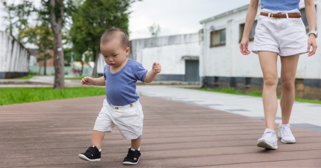 ベトナムの屋外を元気に歩く赤ちゃんと、後ろで見守る大人の女性